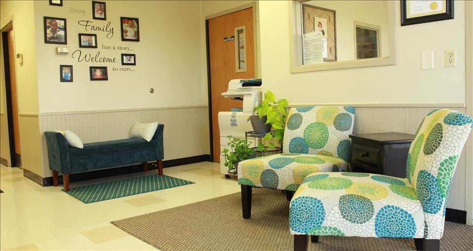 Waiting room with two patterned chairs, a blue bench, and wall decor