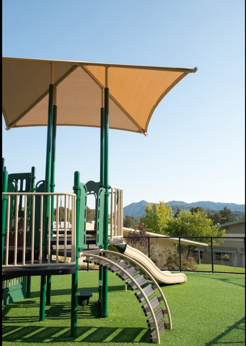 Playground structure with slides and climbing elements on artificial turf