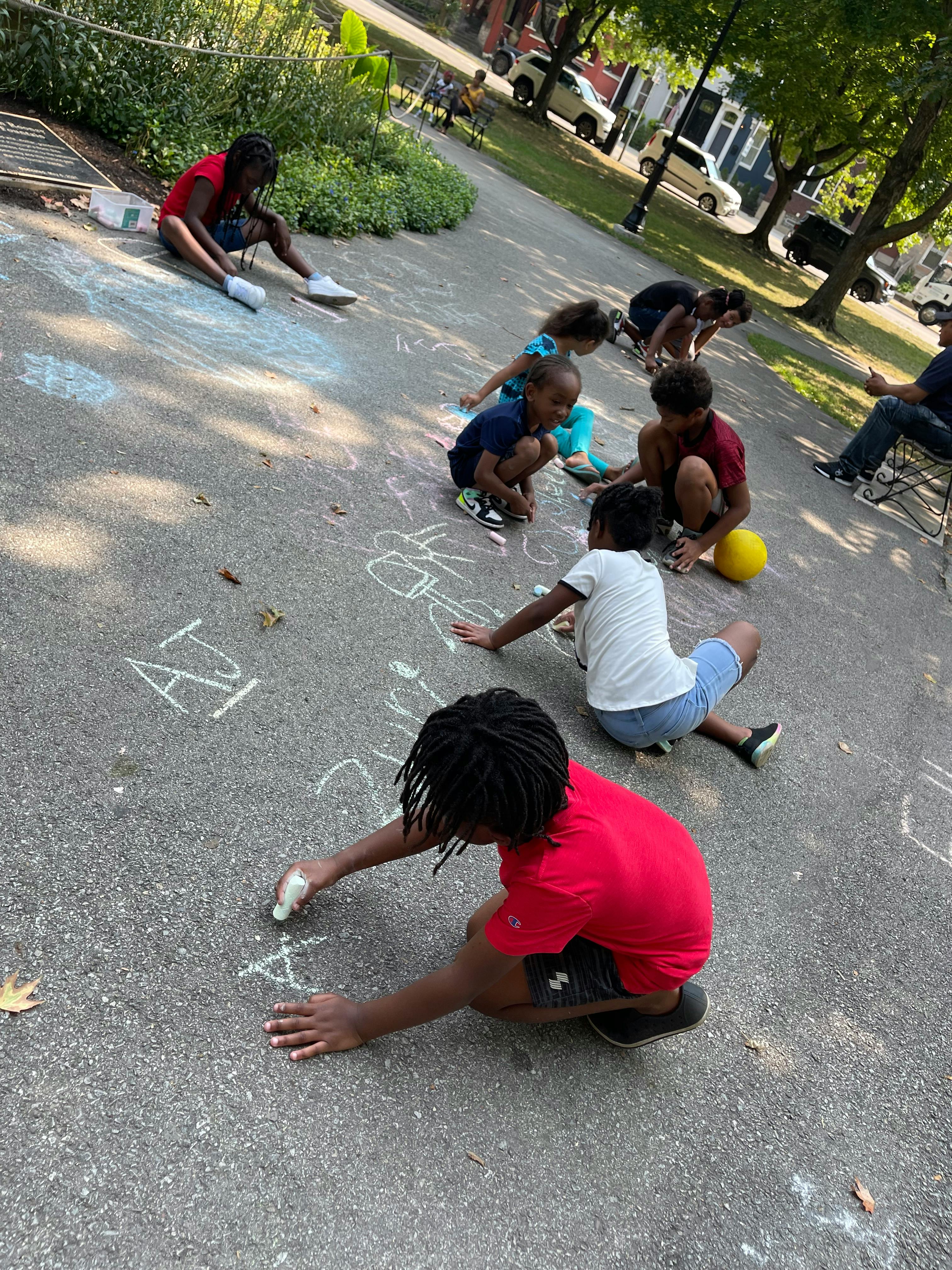 Children drawing with chalk on pavement