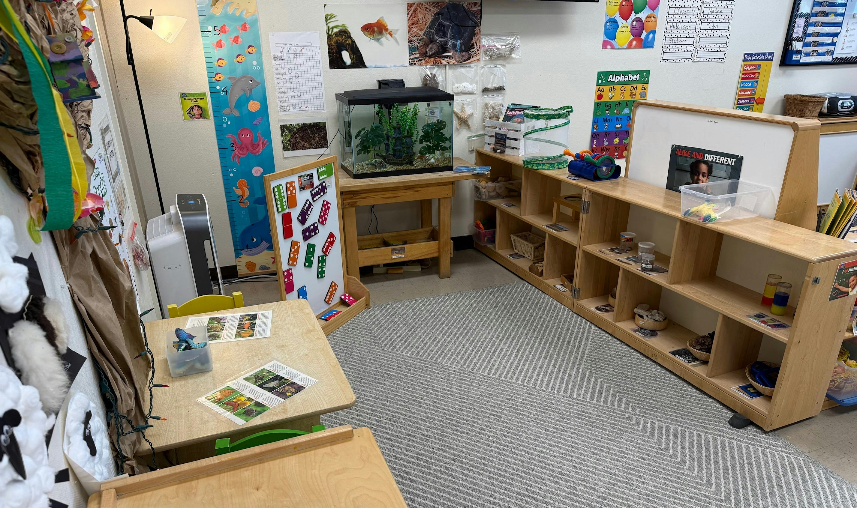 Classroom with tables, shelves, a fish tank, and educational decorations