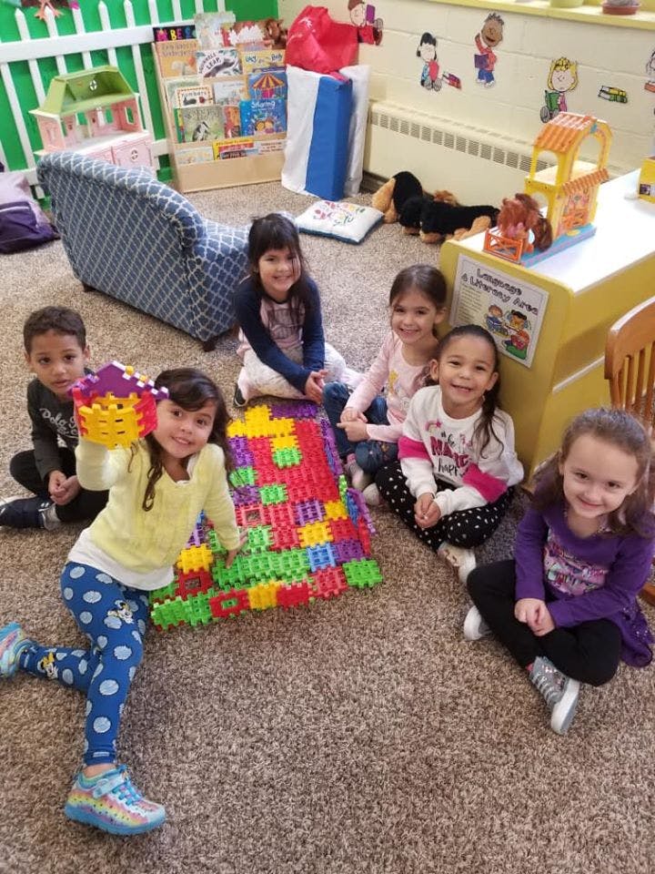 Children playing with colorful building blocks on a carpeted floor