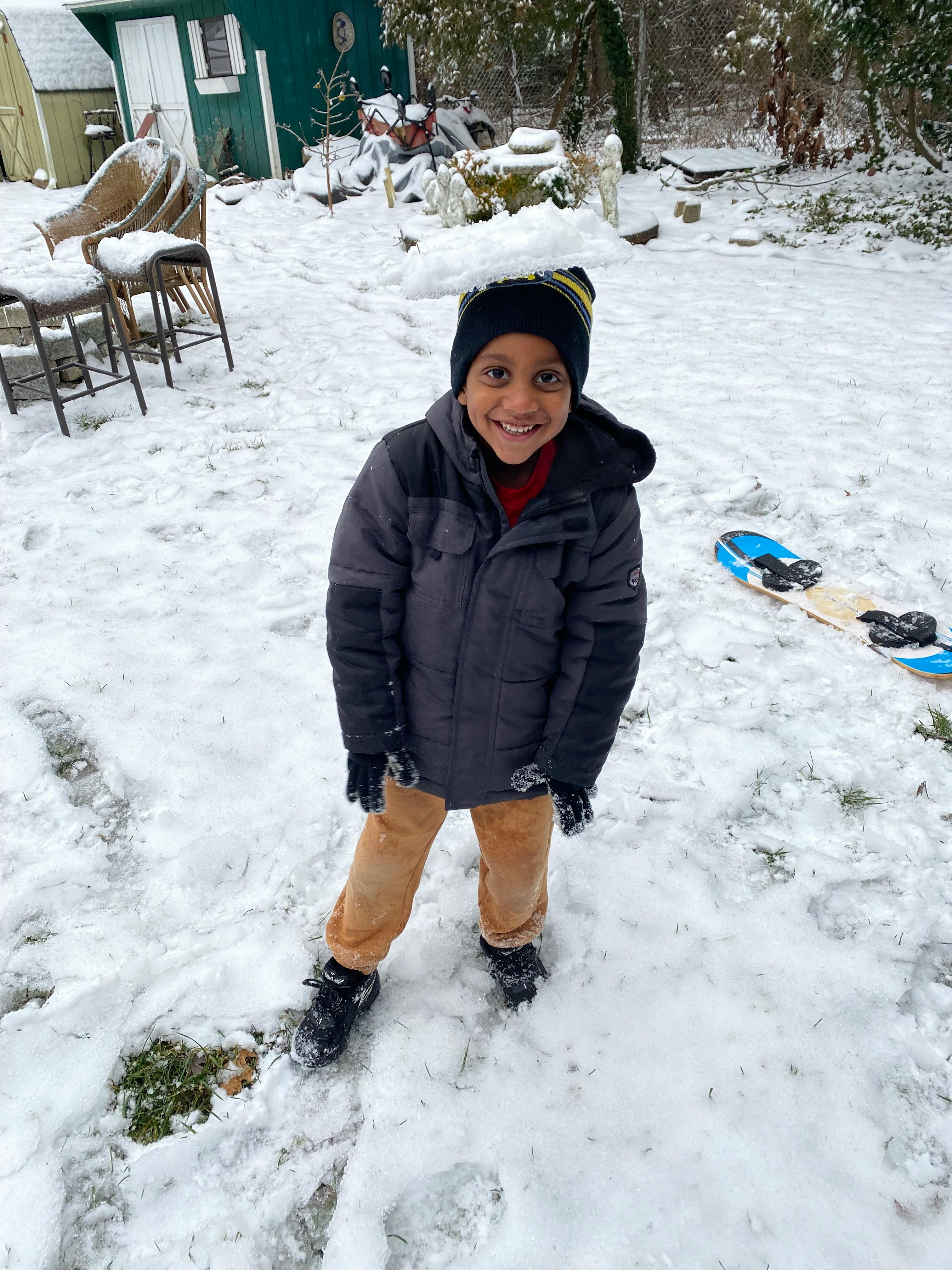 Child in winter coat and hat standing in snow