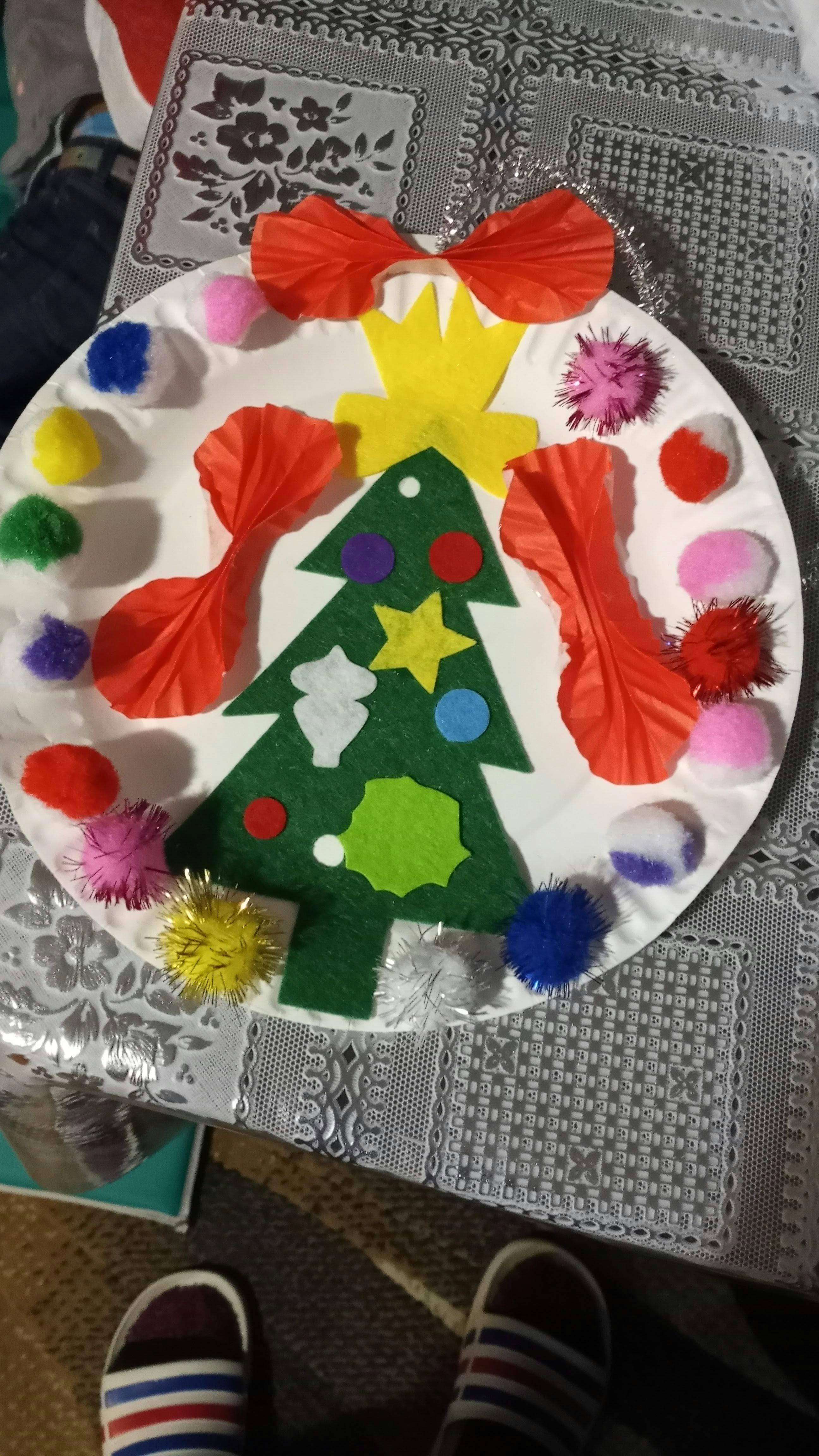Christmas tree craft on a paper plate with pom-poms and paper cutouts