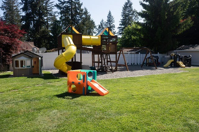 Playground with slides, swings, and a playhouse on grass