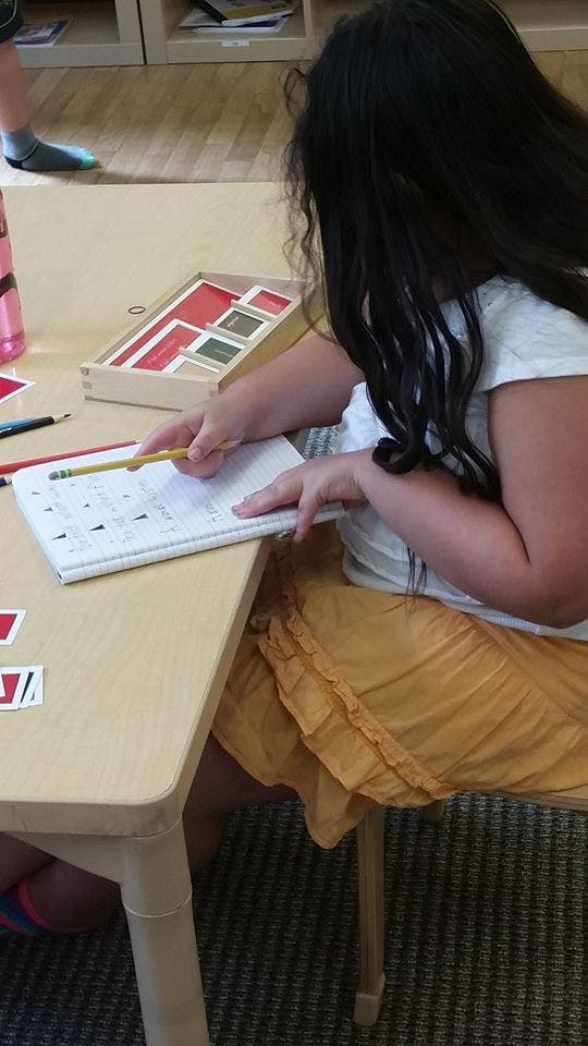 Child writing in a notebook at a table