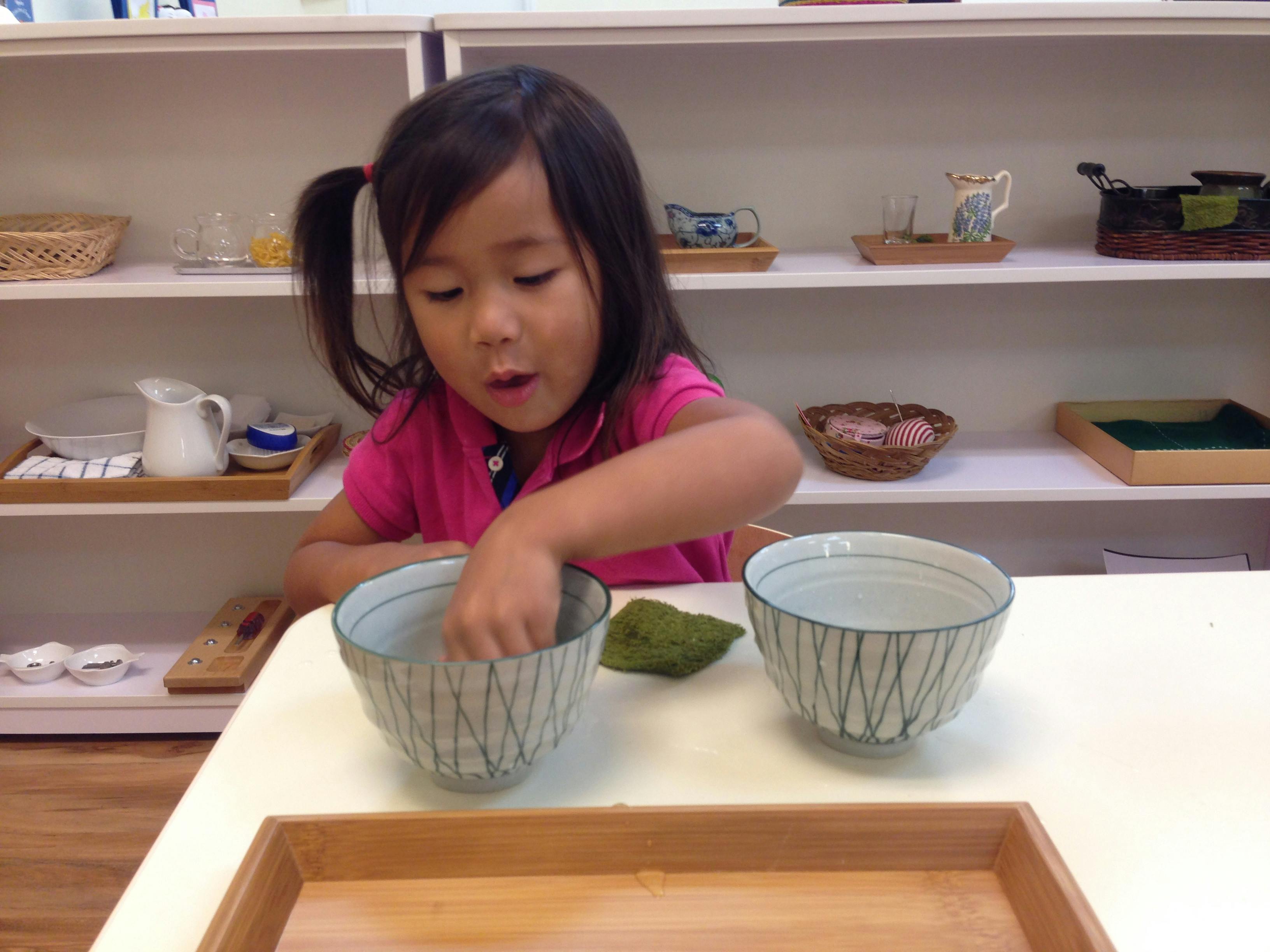 Child reaching into a bowl on a table