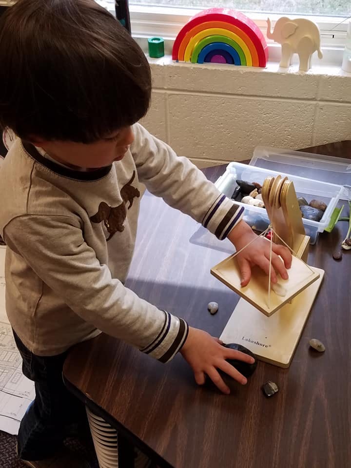 Child playing with a wooden toy on a table