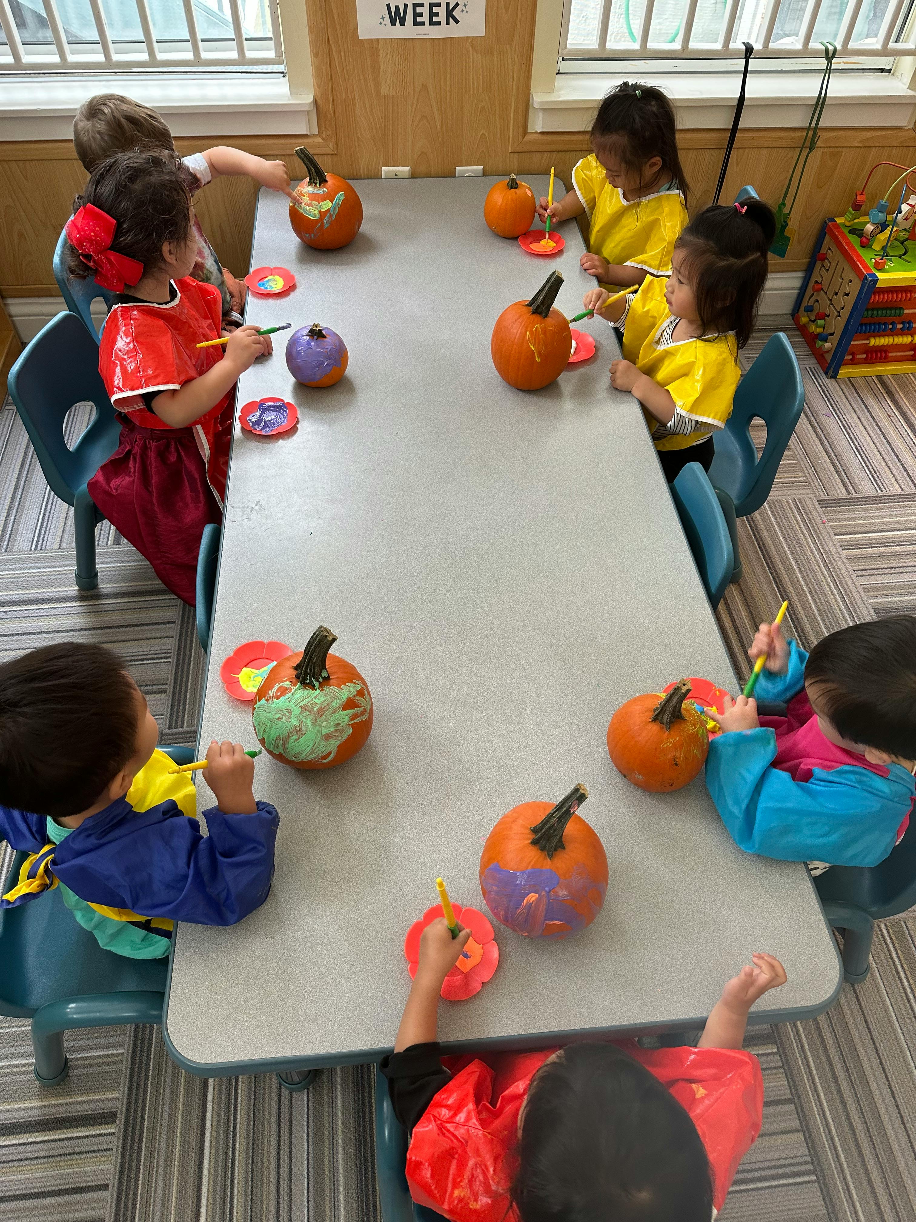 Children painting pumpkins at a table