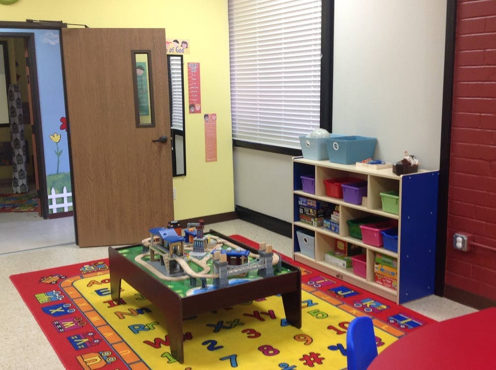 Playroom with a train table on a colorful rug and a storage shelf