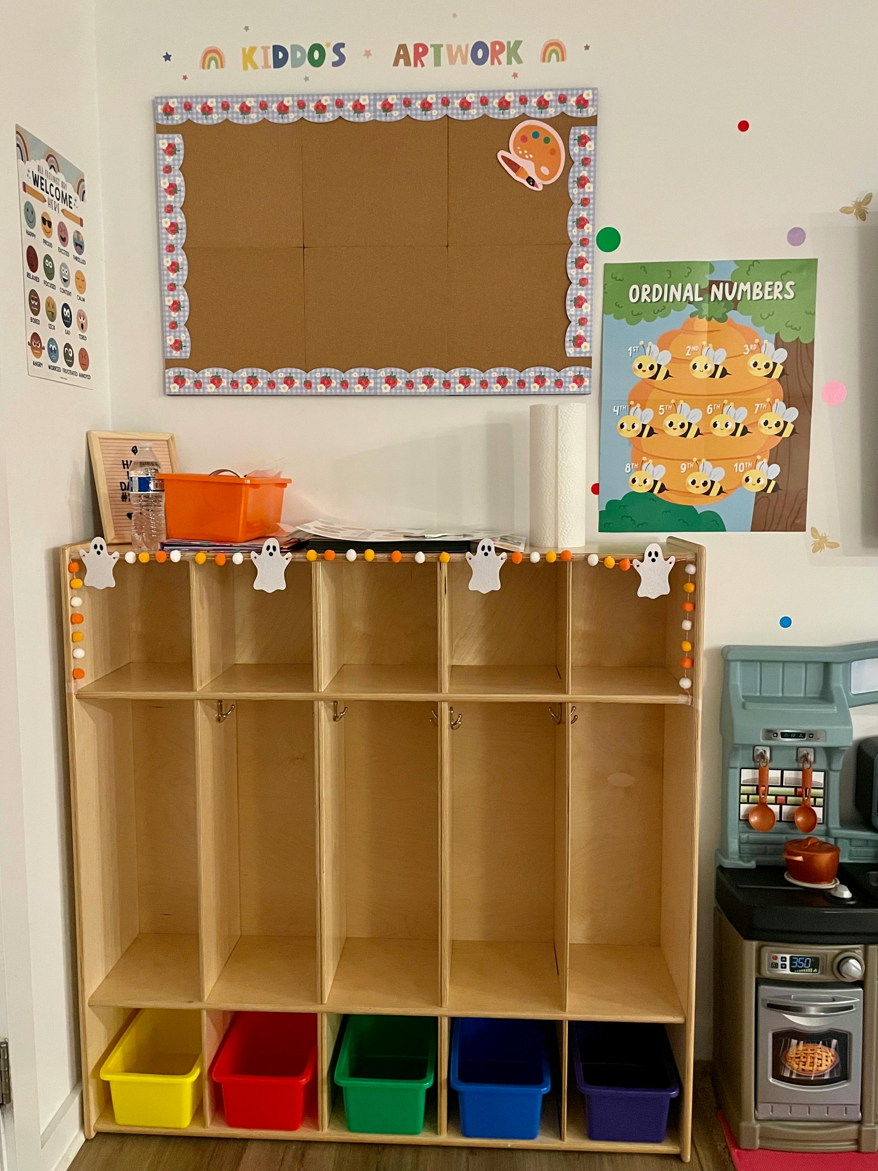 Classroom cubbies with colorful bins and a bulletin board above