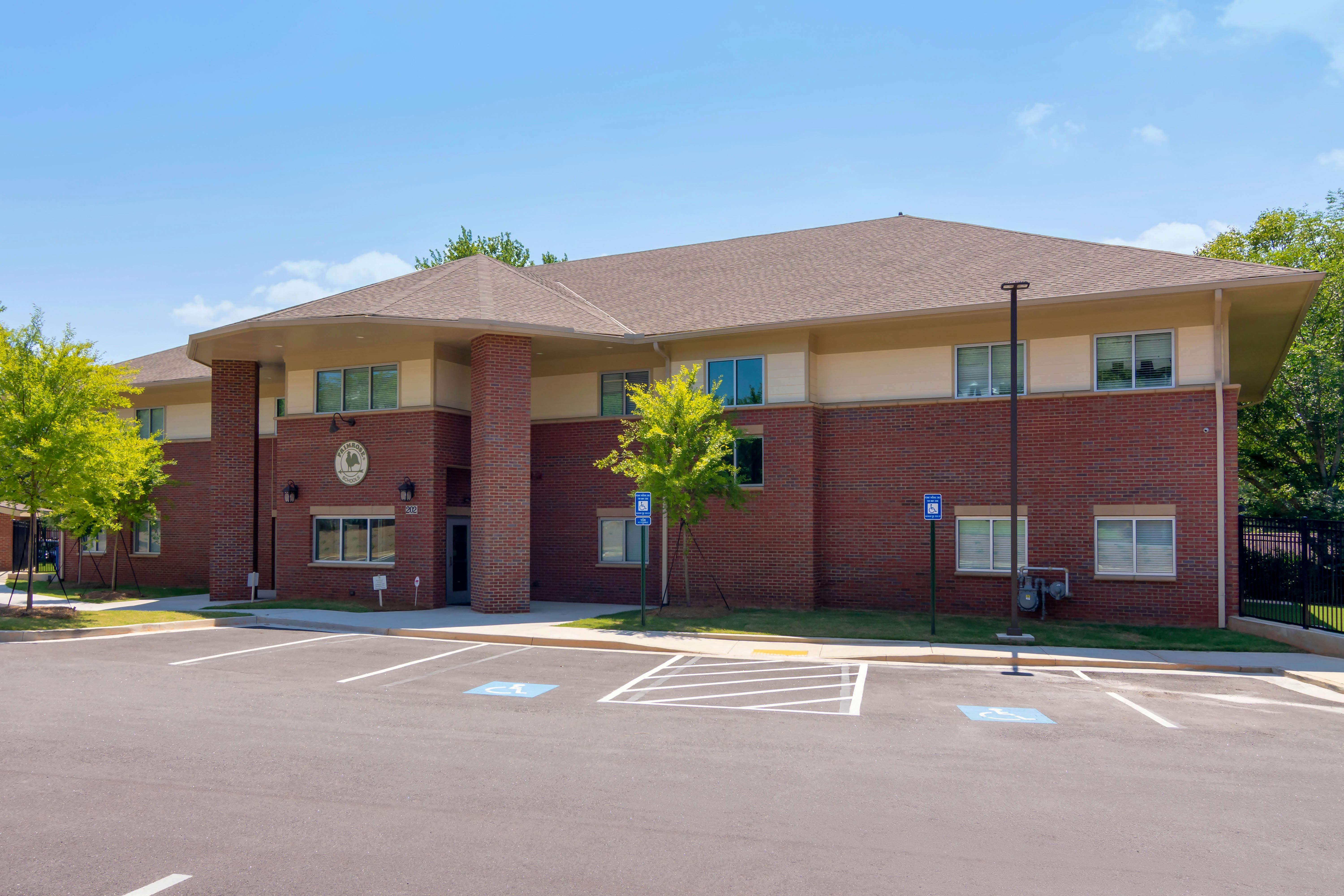 A brick building with beige siding and a parking lot with handicap spaces