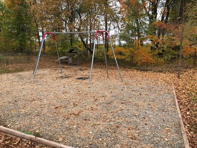Empty swing set on a playground with autumn leaves on the ground