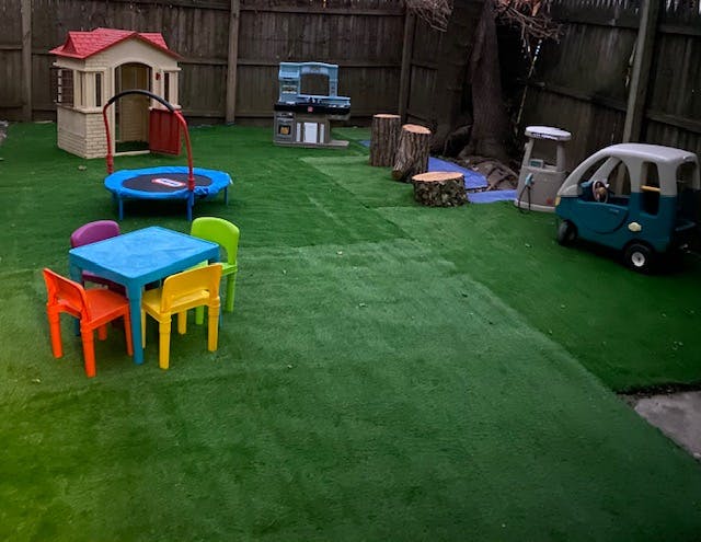 Backyard play area with artificial turf, playhouse, trampoline, and toy car