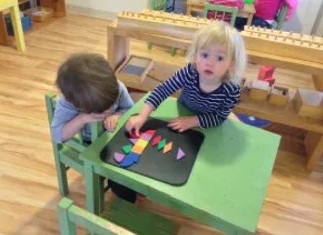 Two children at a table playing with colorful geometric shapes