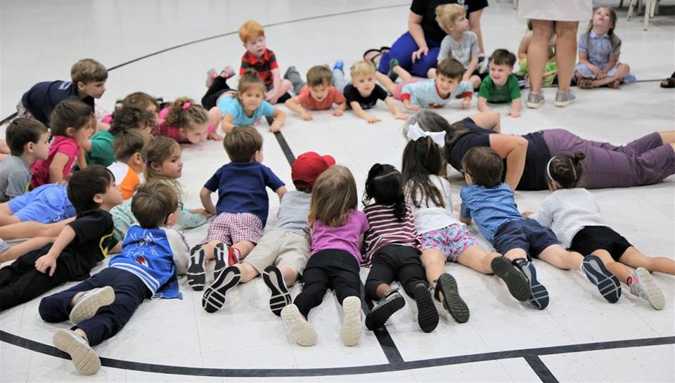 Children and adults lying on a gym floor in a circle