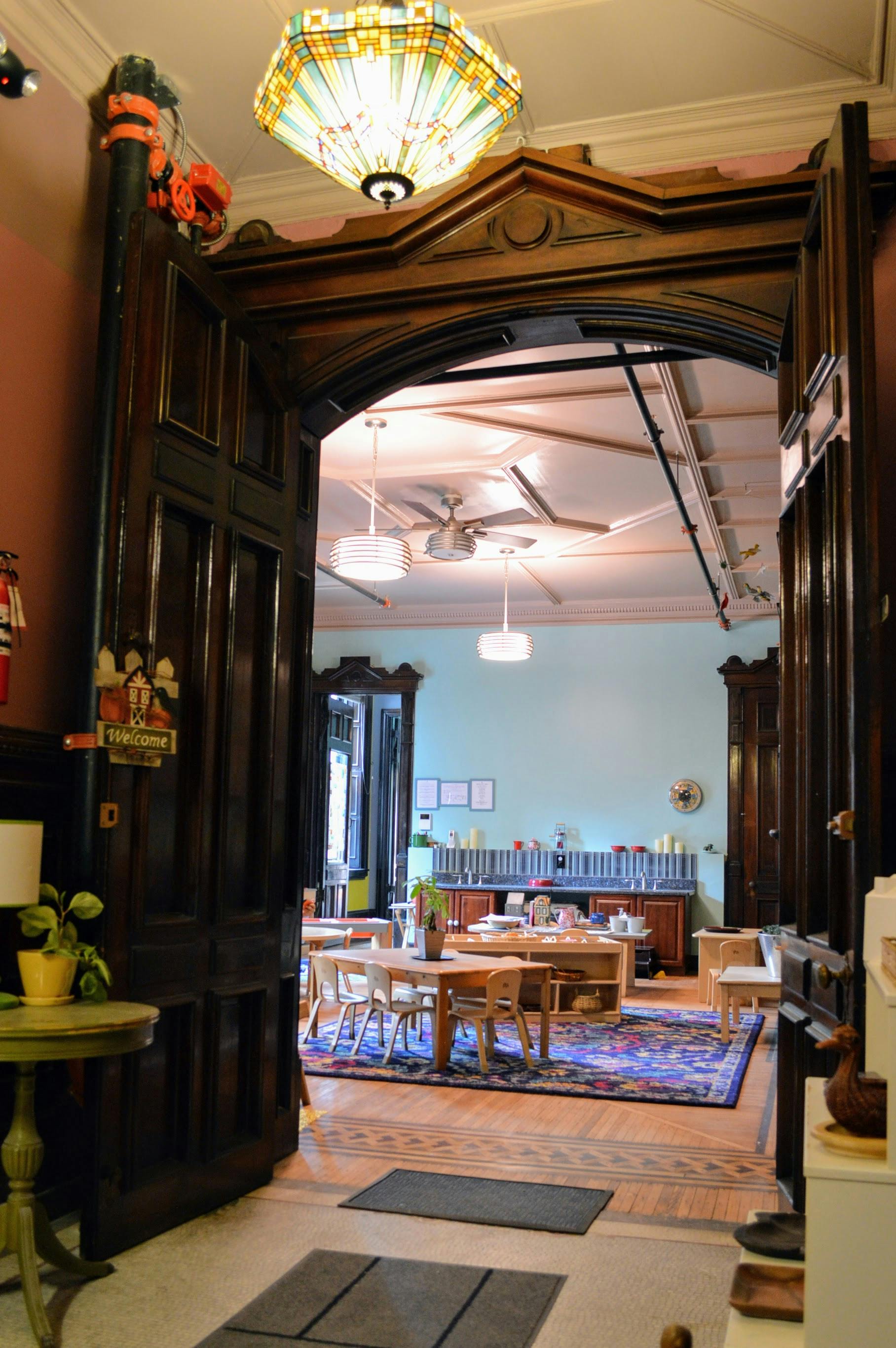 Ornate wooden doorway opening into a room with tables and chairs