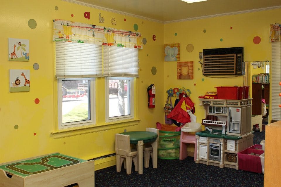 Playroom with yellow walls, small table and chairs, and toy kitchen