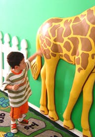 Child touching a giraffe statue