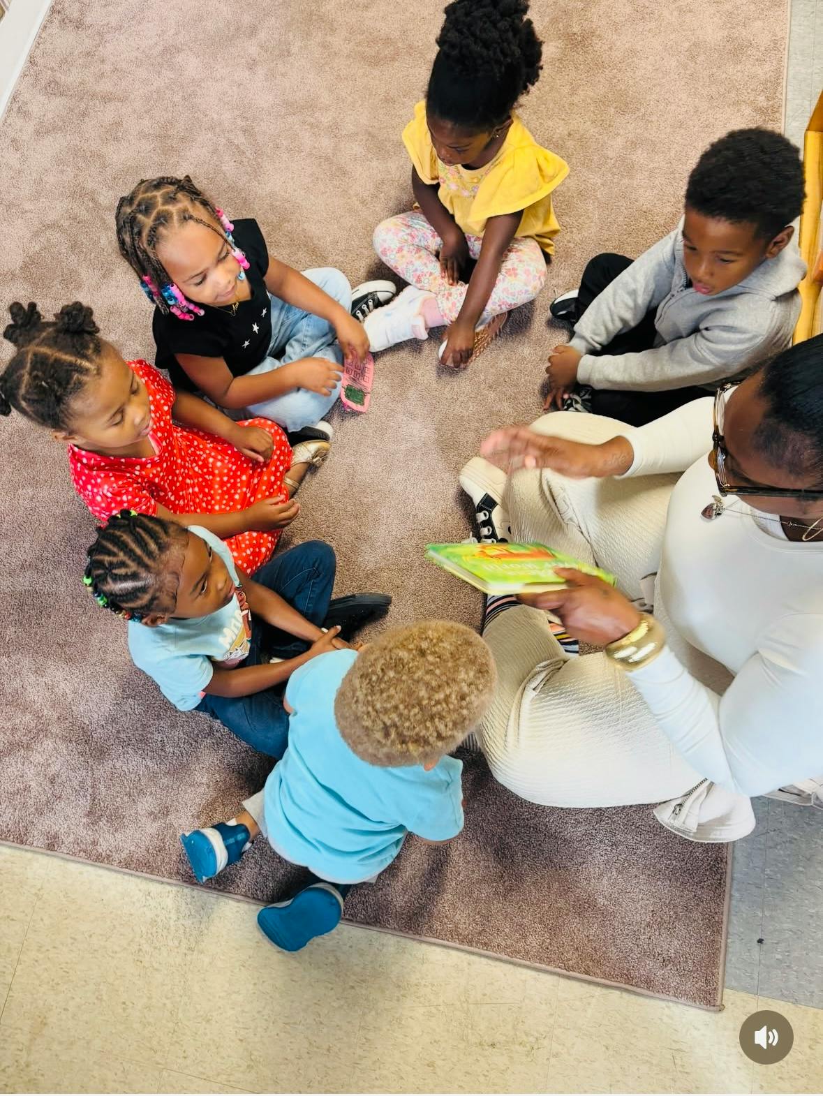 Adult reading a book to a group of children sitting in a circle