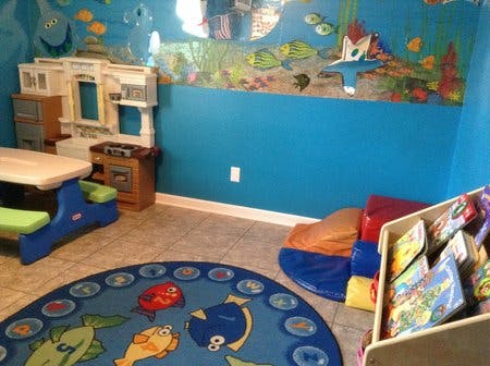 Playroom with blue walls, toy kitchen, and fish-themed rug