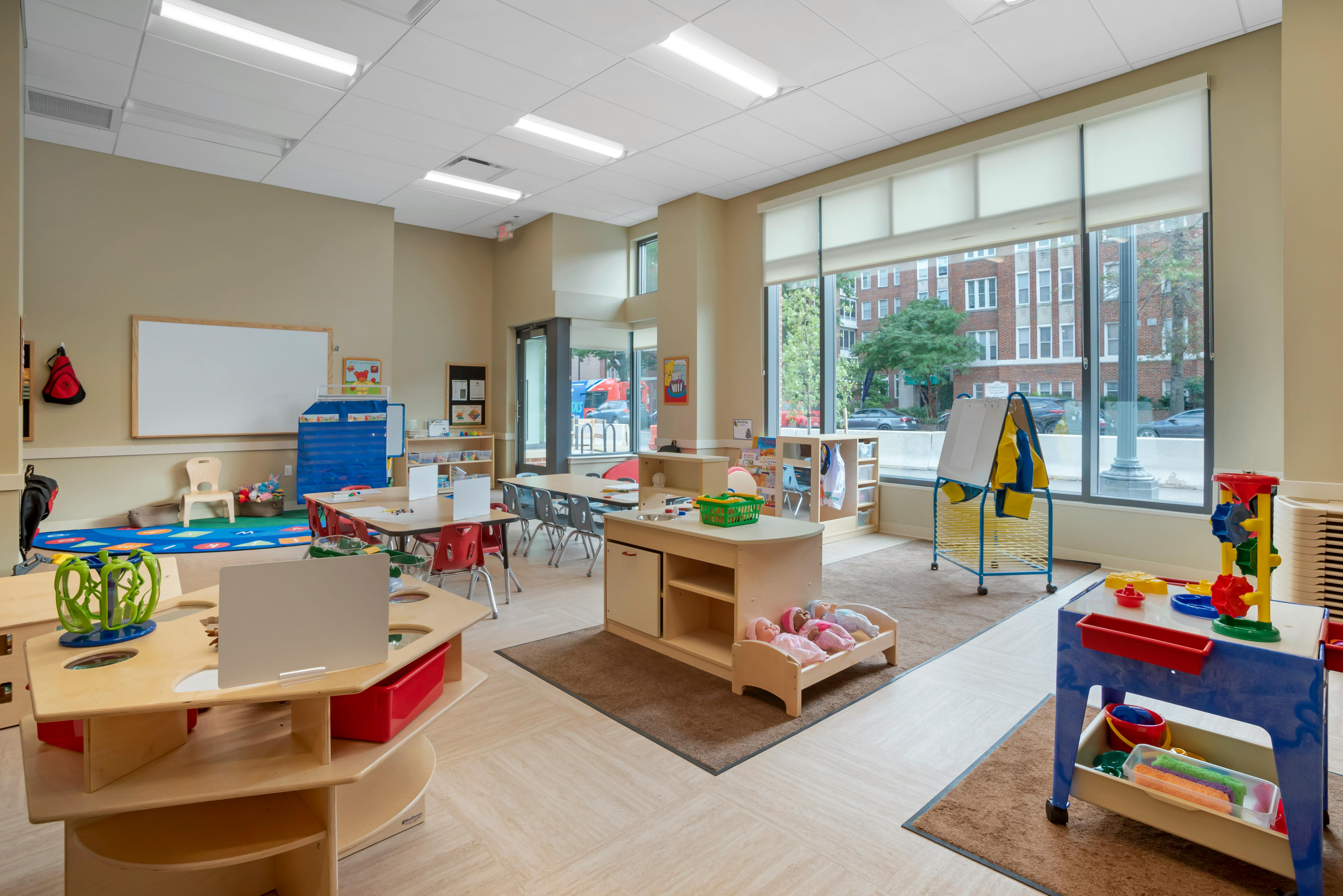 An empty daycare classroom with tables, chairs, and play areas