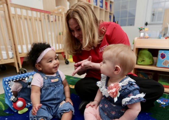 Adult interacting with two babies in a classroom