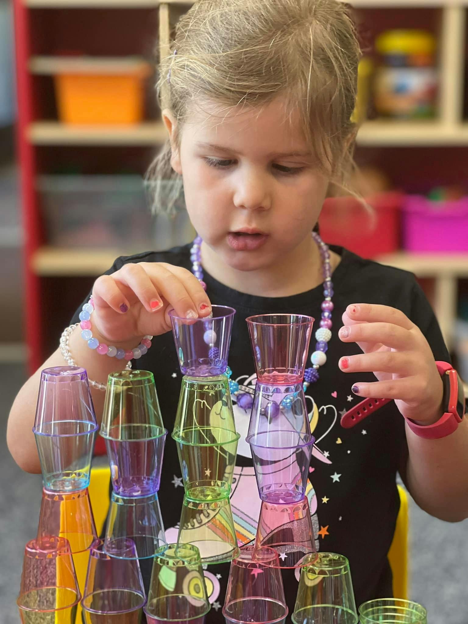 Child stacking colorful plastic cups
