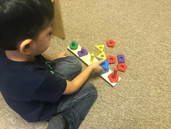 Child playing with a shape sorter toy on the floor
