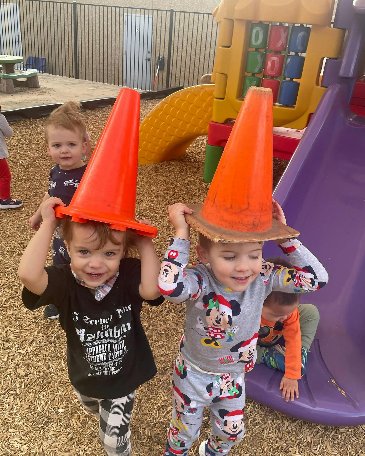 Two children with traffic cones on their heads on a playground
