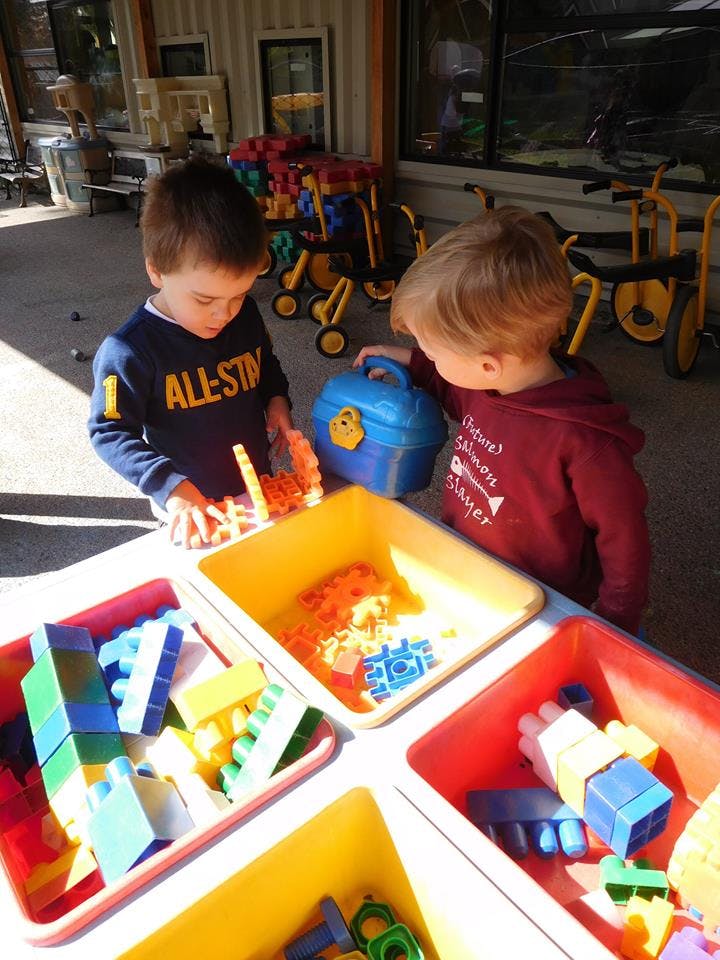 Two children playing with colorful building blocks at a table