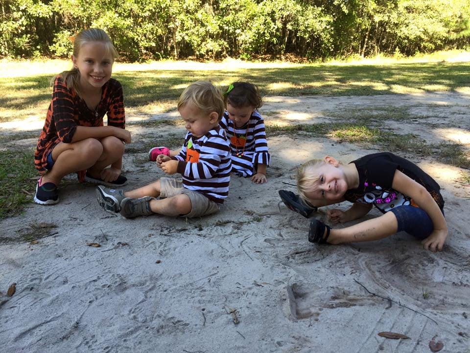 Four children playing on the ground outdoors