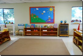 Empty classroom with shelves, a rug, and a large wall decoration