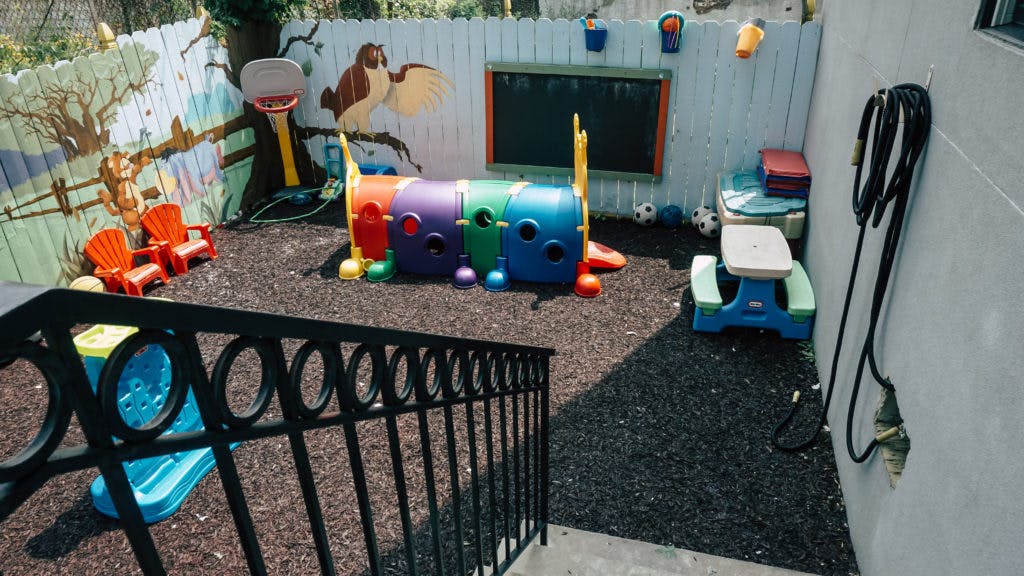 Outdoor play area with a colorful tunnel, small chairs, and a picnic table