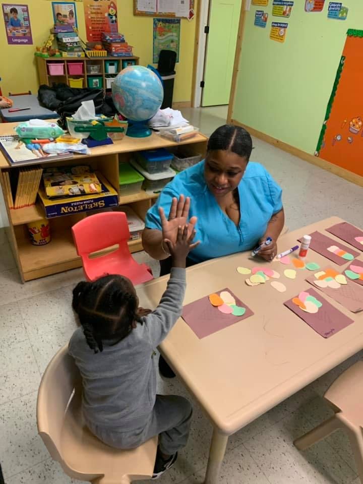 Adult and child high-fiving in a classroom