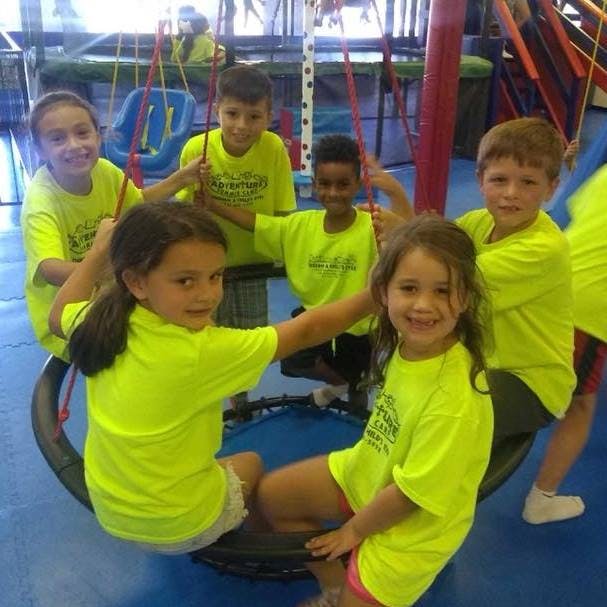 Group of children in bright yellow shirts playing on swings