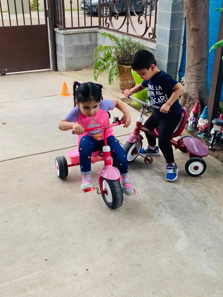 Two children riding tricycles outdoors