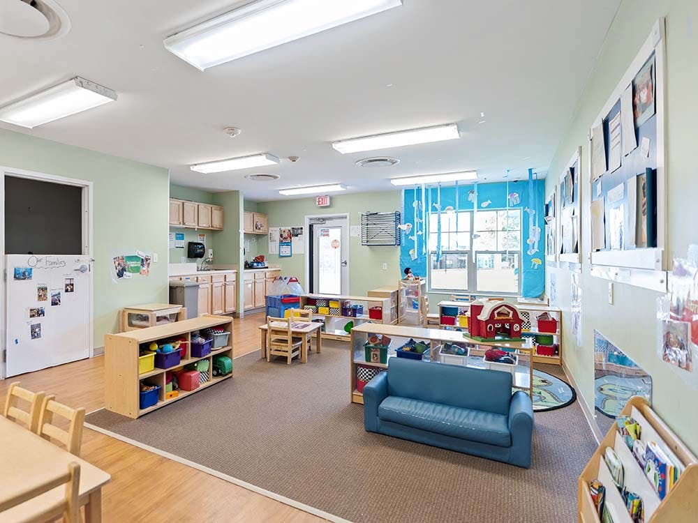A colorful classroom with child-sized furniture and a blue sofa