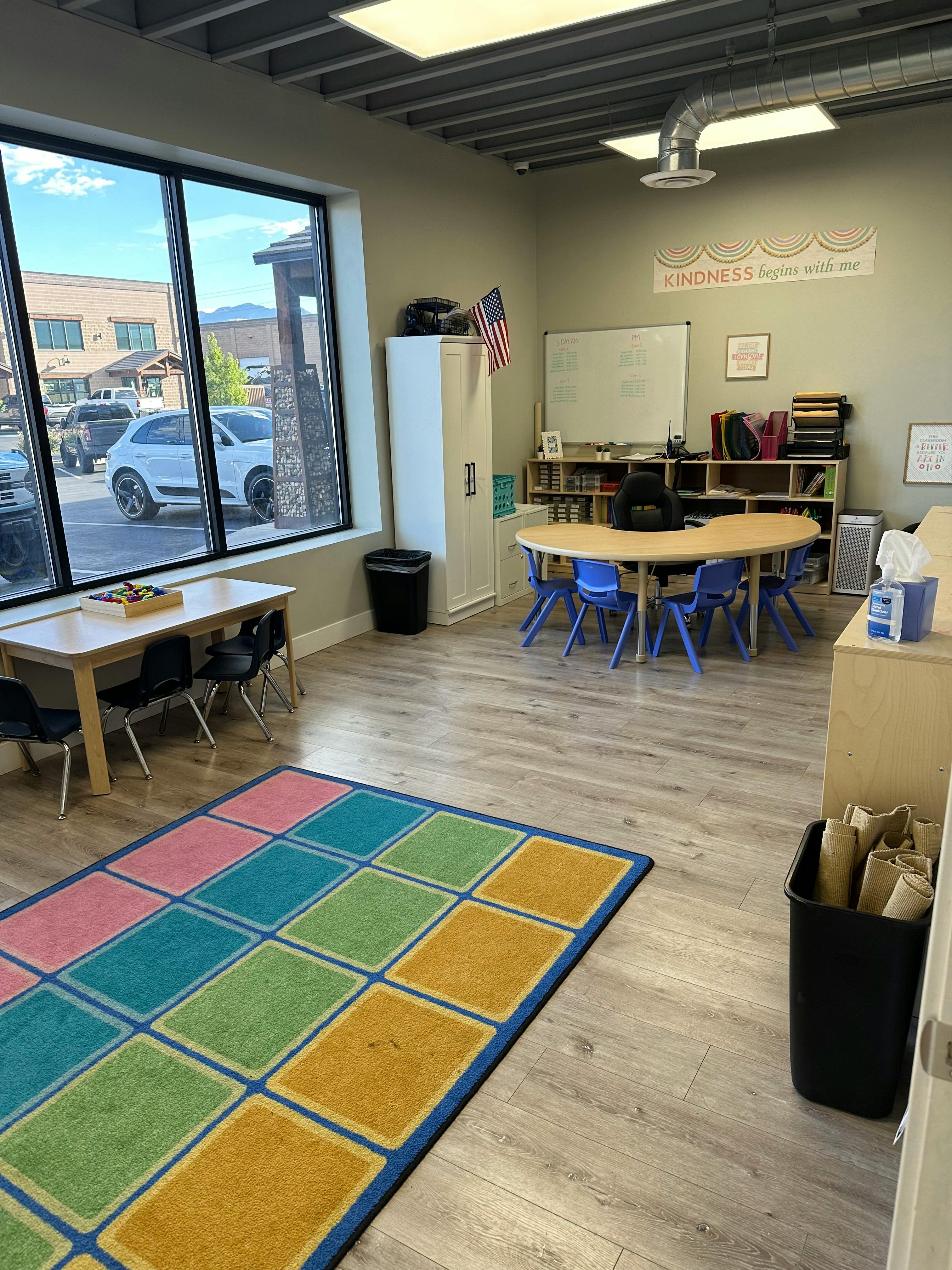 Classroom with tables, chairs, and a colorful rug