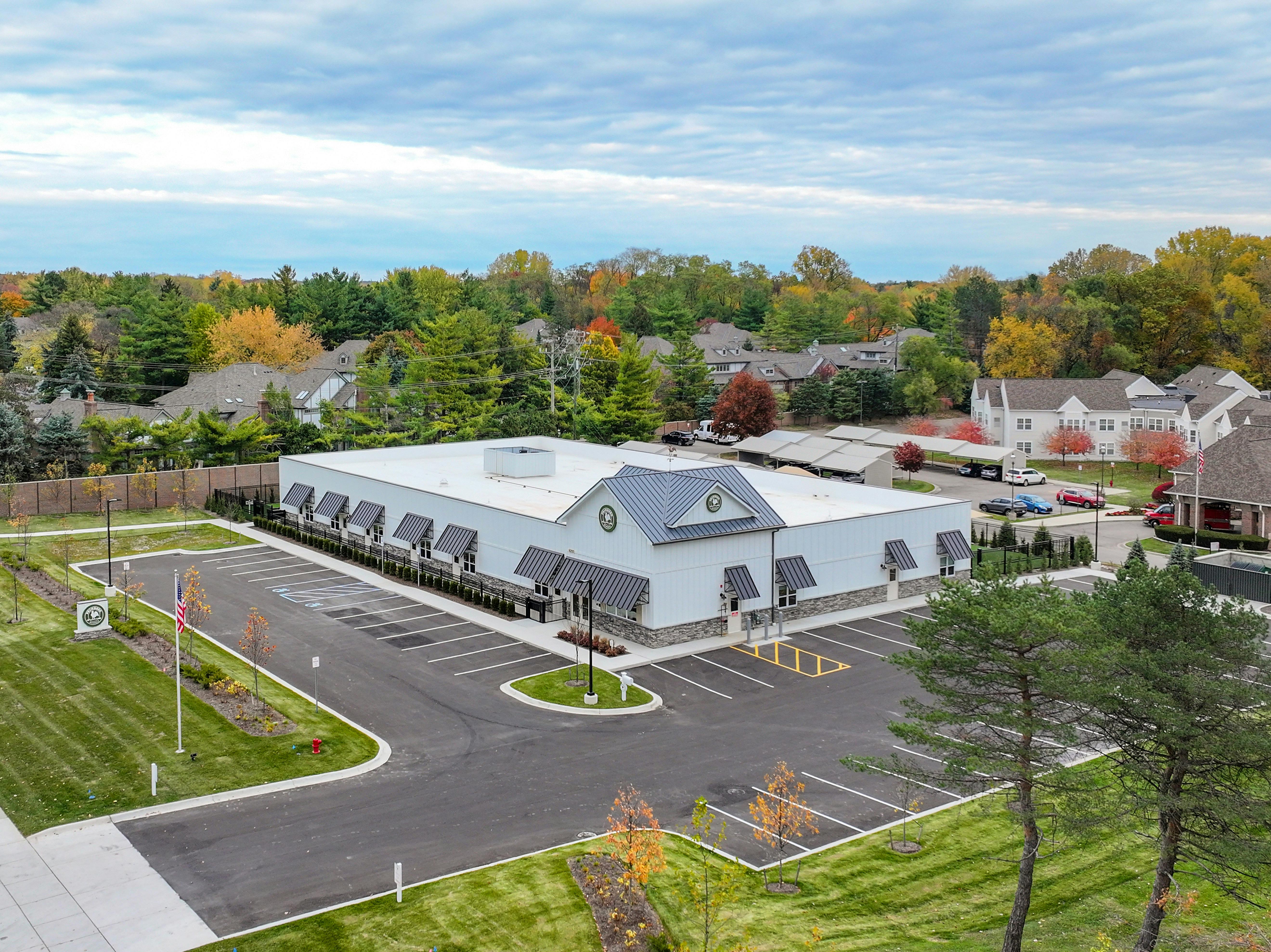 Aerial view of a white building with black awnings next to a parking lot