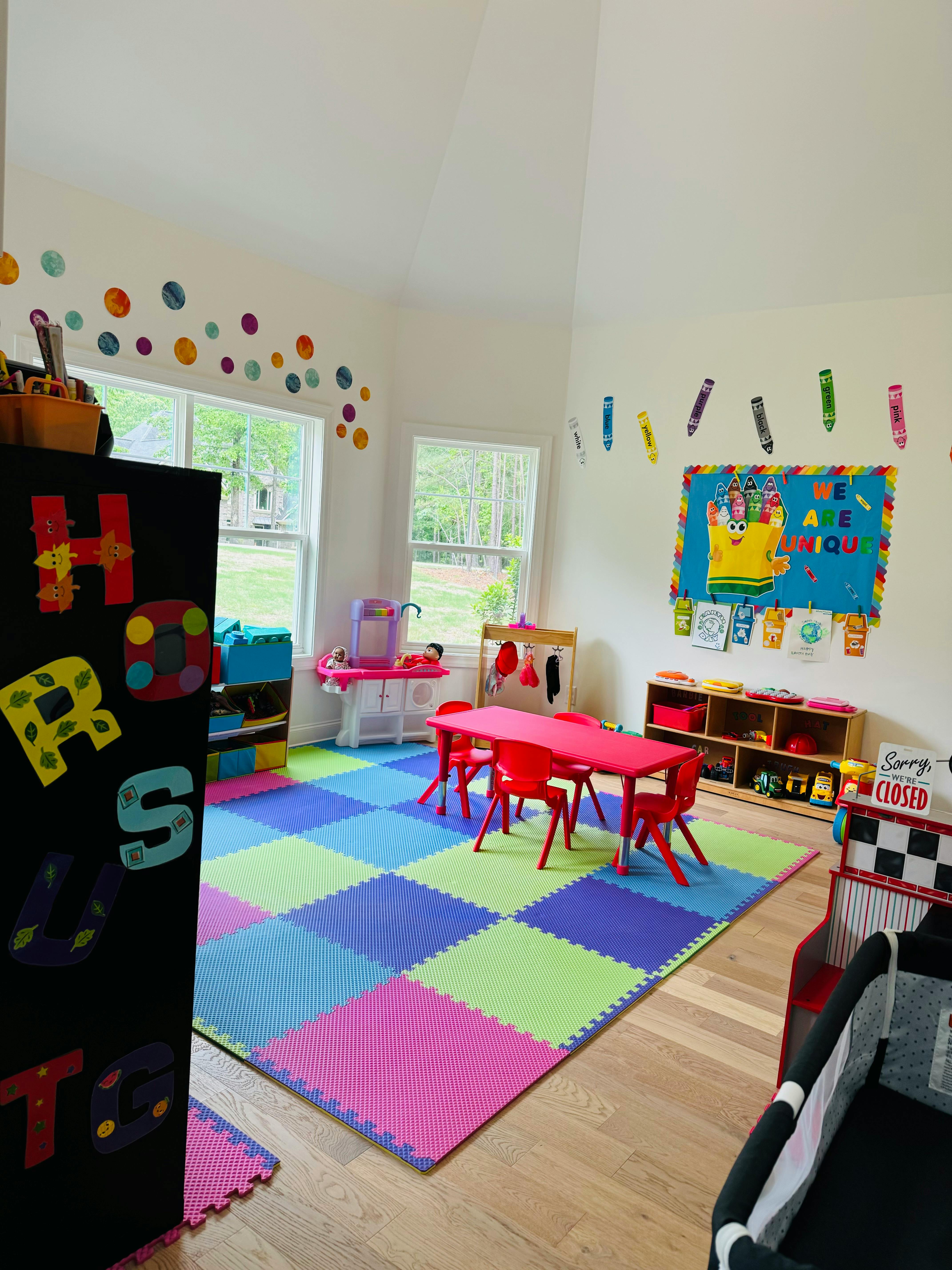A colorful playroom with a checkered mat, small red table and chairs, and toys