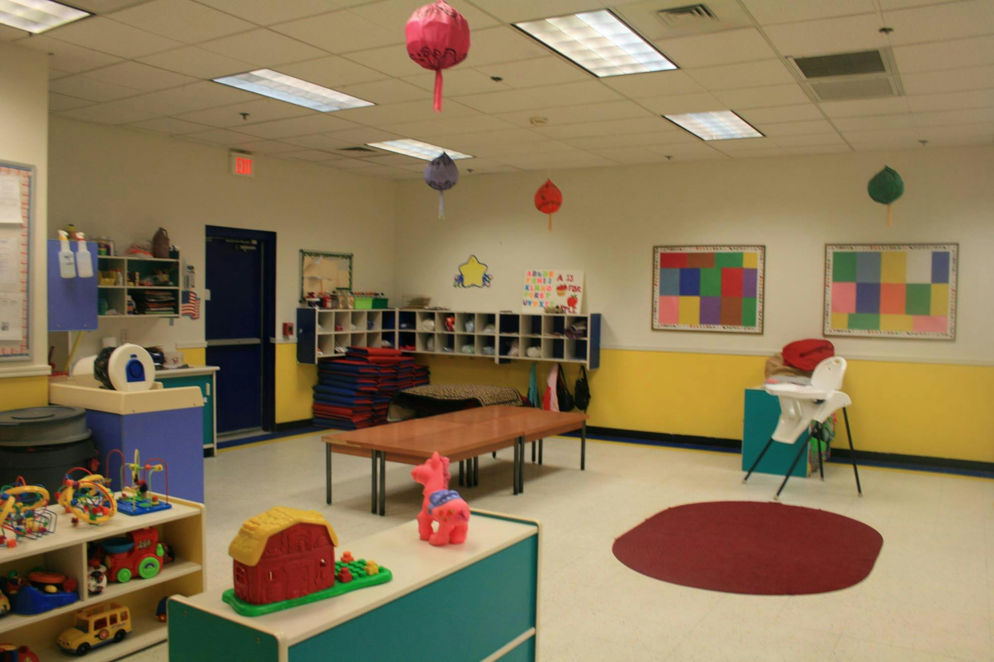 Empty classroom with toys, shelves, and a high chair