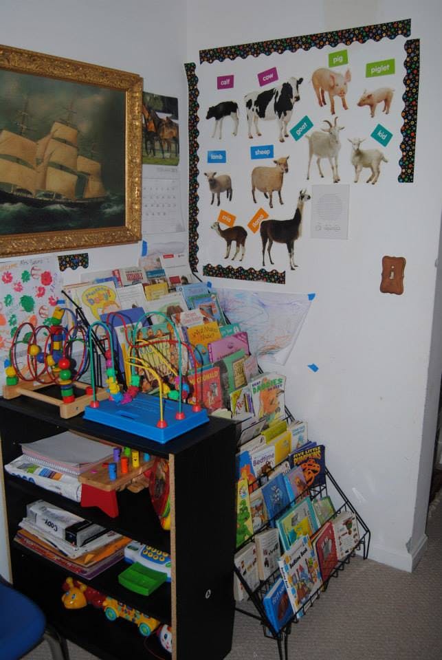 Children's toys and books in a room with a farm animal poster on the wall