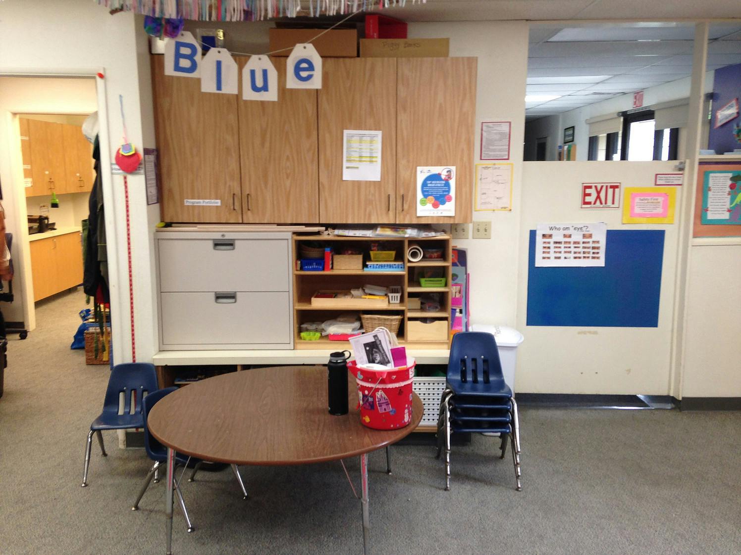 Classroom with a round table and chairs, cabinets, and a bulletin board