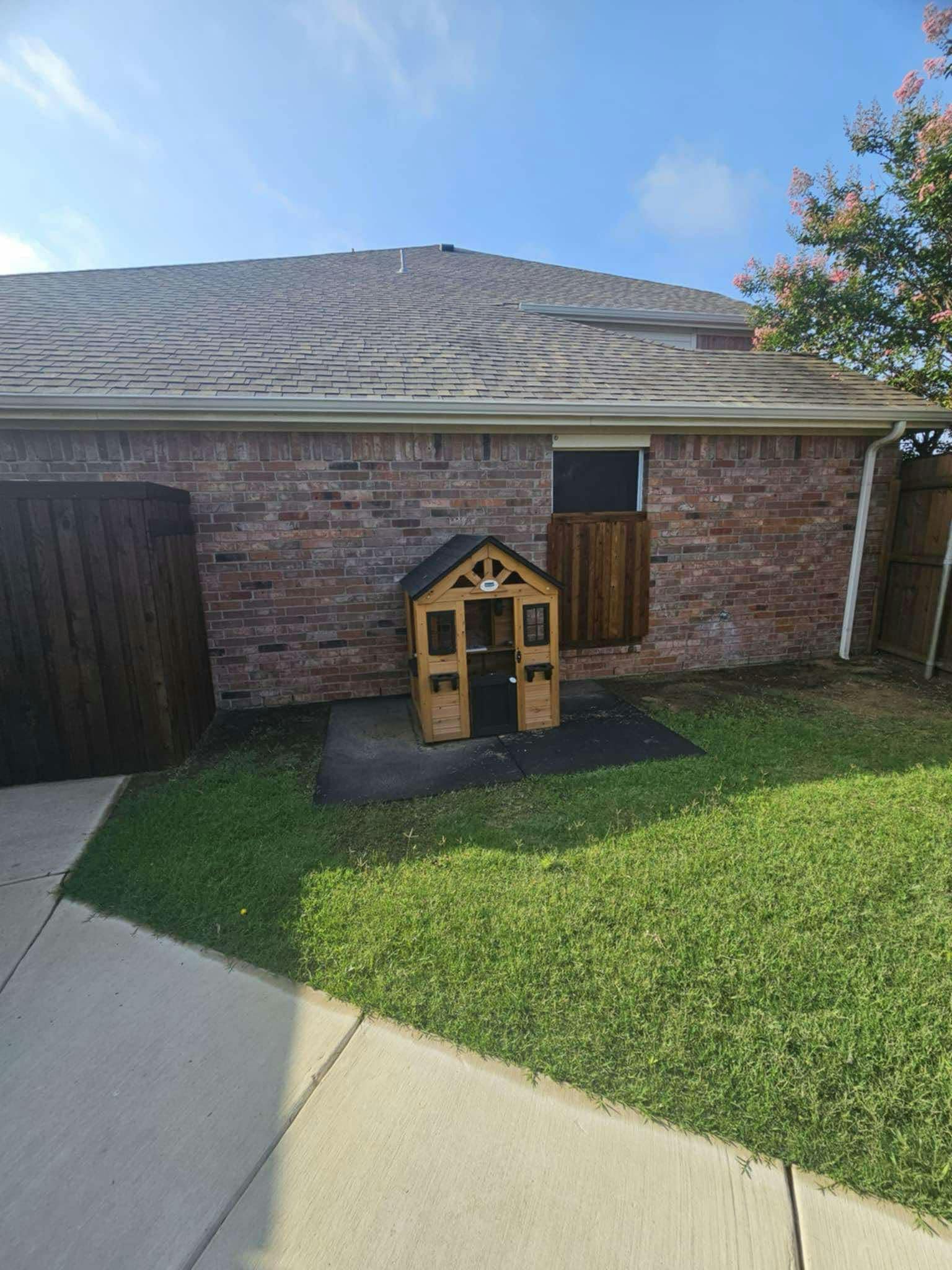 Small wooden playhouse next to a brick building