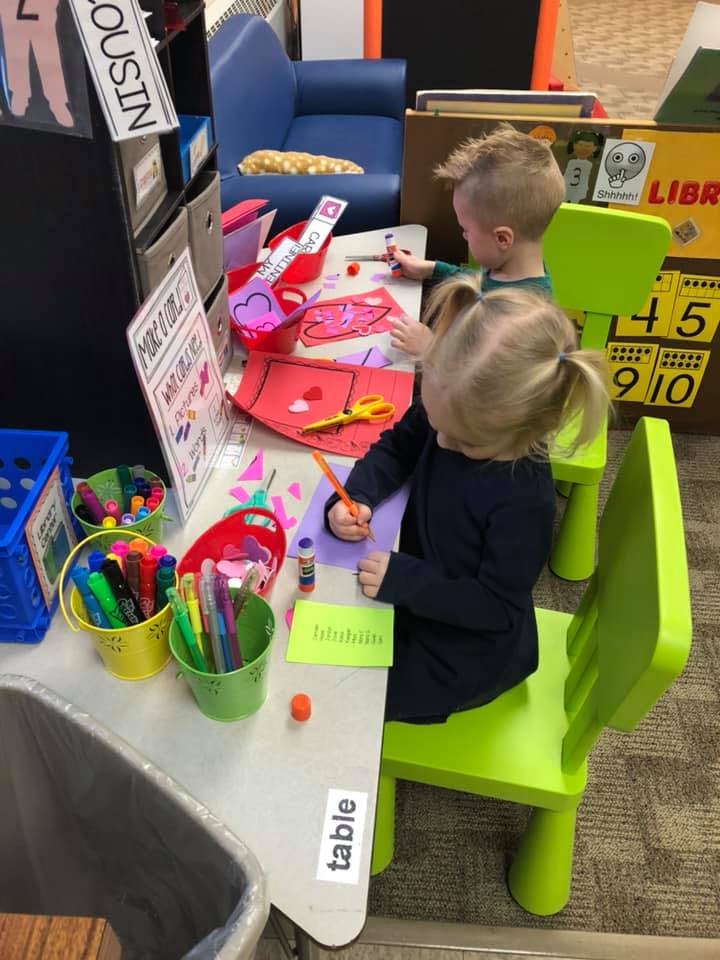 Two children sitting at a table doing crafts