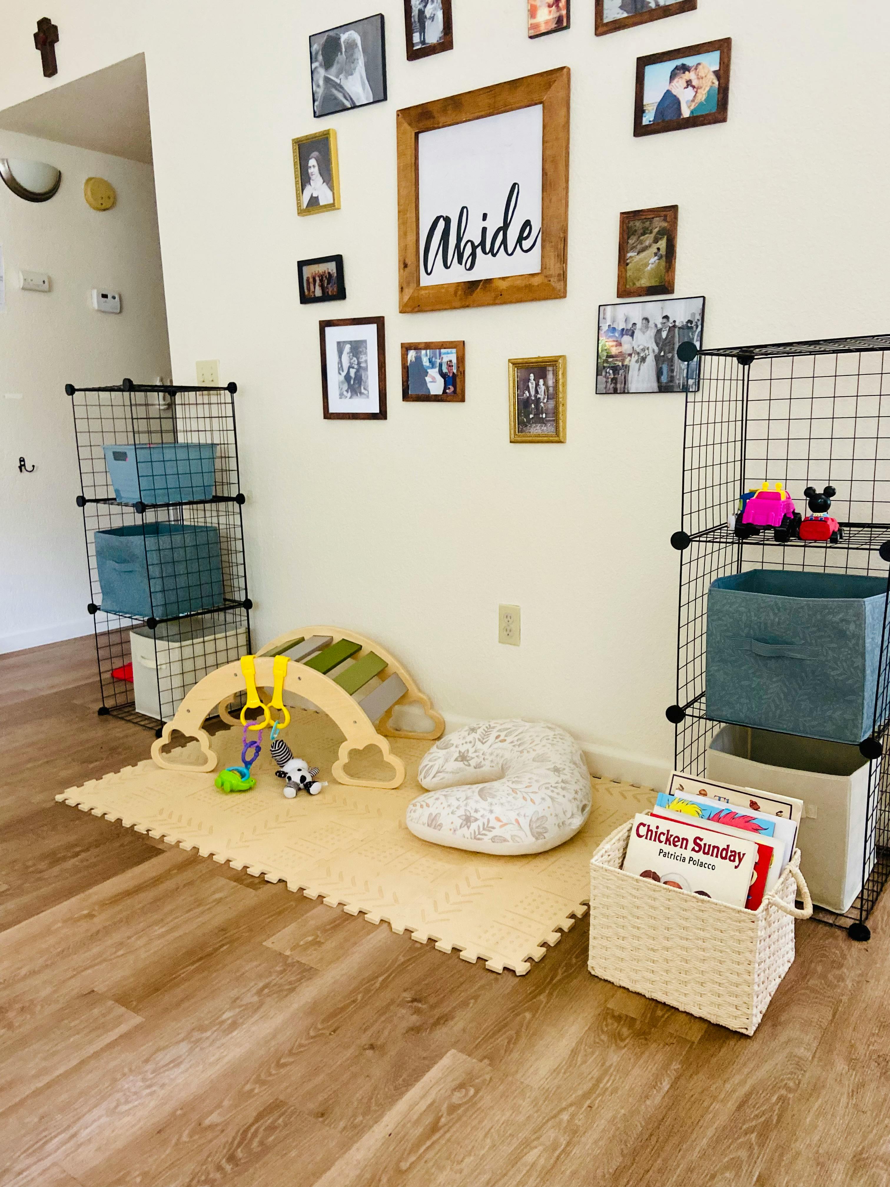 Play area with a mat, baby gym, and storage shelves