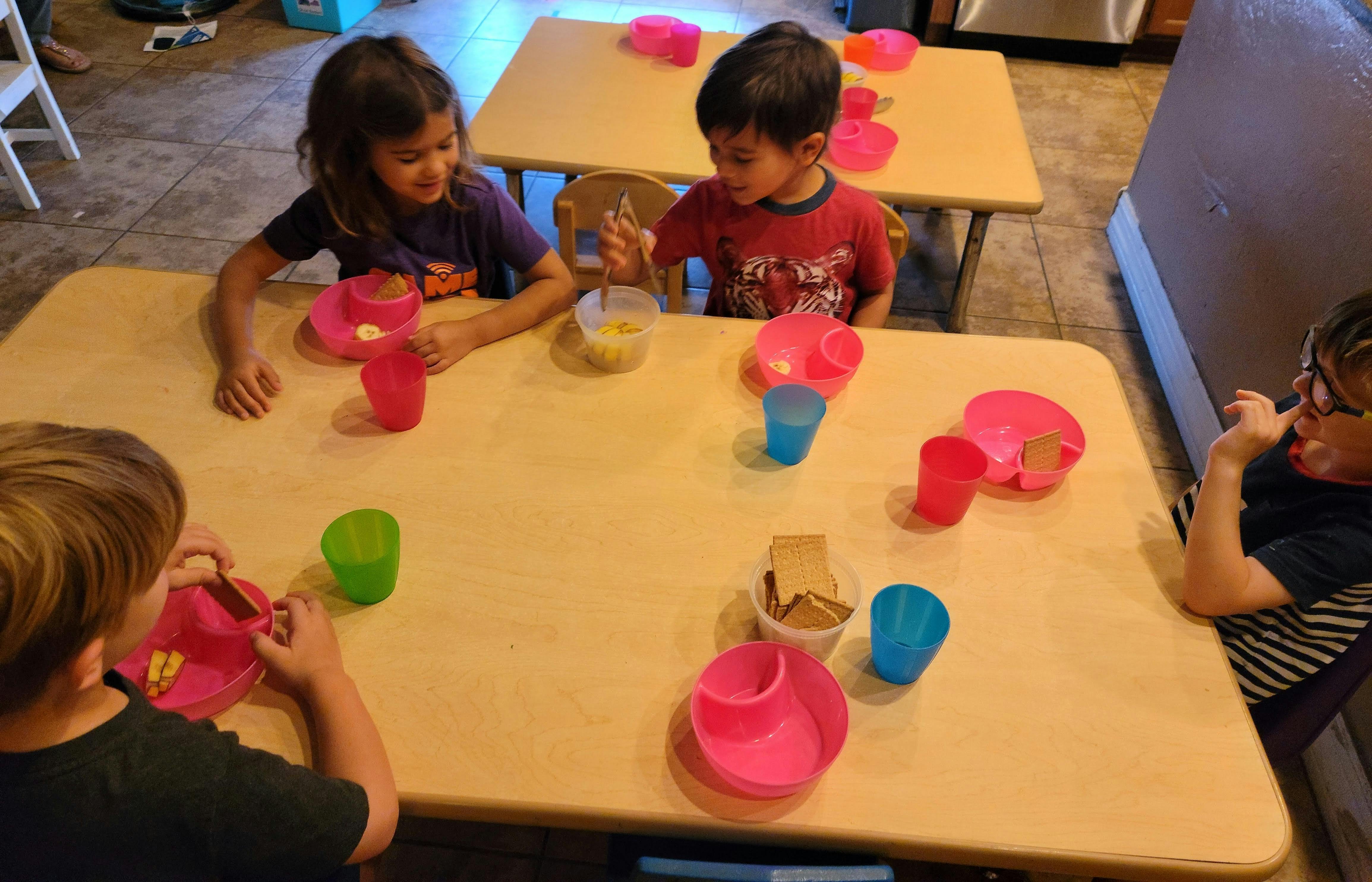 Children sitting at tables with plates and cups