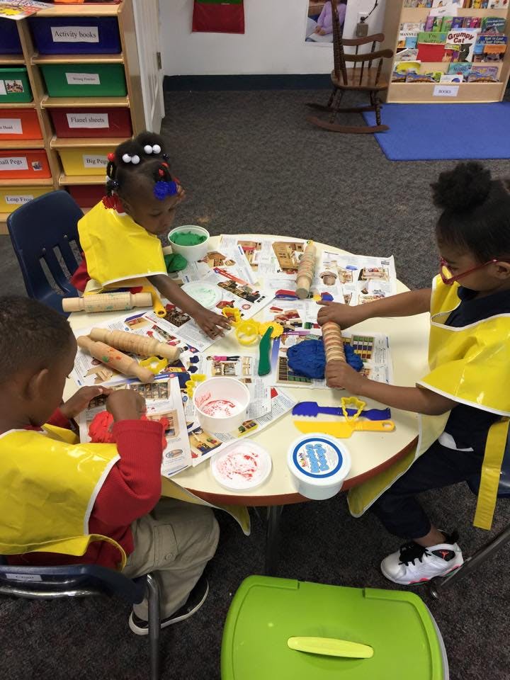 Three children playing with modeling clay at a table