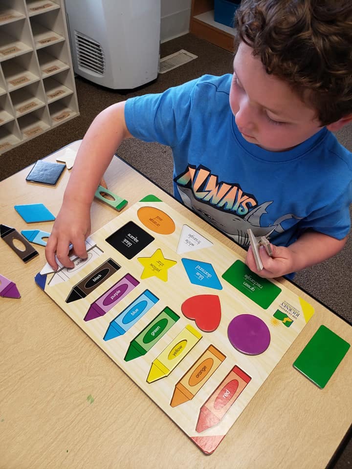 Child playing with a shape and crayon puzzle