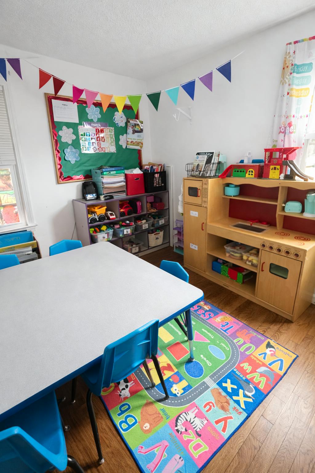 Children's classroom with a play kitchen, toy shelves, and small table with chairs